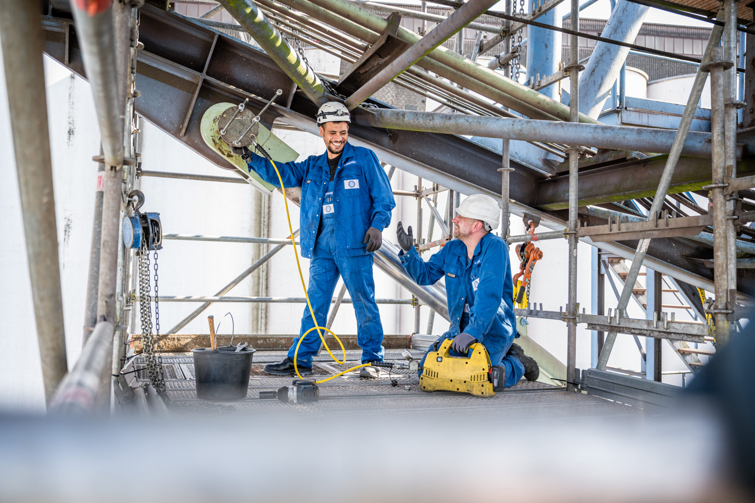 Zwei Industriearbeiter im Gerüstbereich bei Montagearbeiten im Dialog